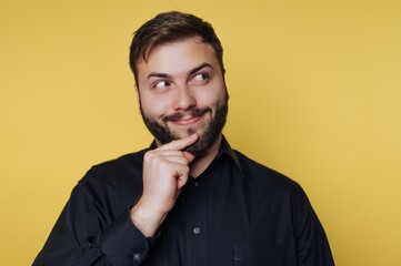 Fototapeta premium Man in black shirt with thoughtful expression on yellow background.