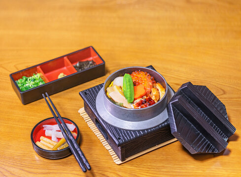 Japanese kamameshi rice dish cooked in an iron kama pot with ikura red caviar, edamame soybeans in the pod, unagi grilled eel, quail egg, bamboo shoots, flower shaped carrot, tsukemono pickles.