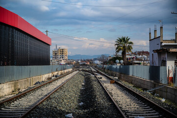Fototapeta premium Railway tracks in Durrës, Albania, forming part of the city’s transportation infrastructure. The image captures everyday urban scenery and reflects the role of rail transport in the local environment 