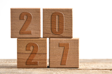 Wooden toy blocks forming number 2027, New Year goals and future planning concept.