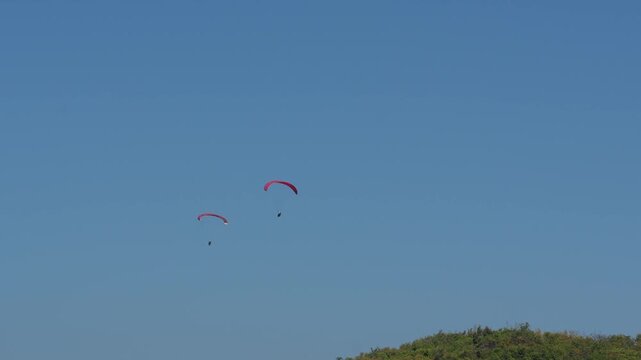 Two paragliders flying in clear blue sky