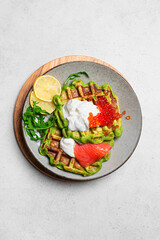 Healthy low carb breakfast with green avocado waffles, salmon, red caviar, ricotta cheese