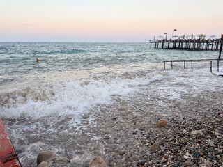 The sea reflects soft evening light under cloudy sky with distant horizon line. Calm waves, marine ecology and coastal landscape in seasonal outdoor environment.