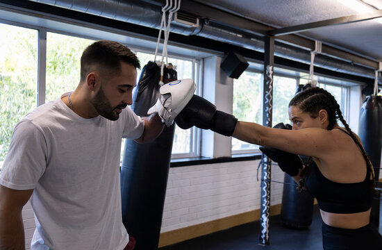 Boxing Coach Training Female Athlete with Focus Mitts in Gym