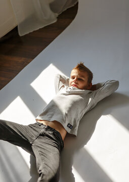 Young boy lying on the floor indoors. Child resting on the floor in a home environment. Casual lifestyle scene with a kid relaxing inside a room
