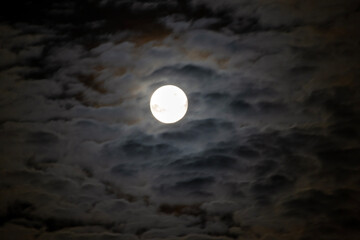 Full moon among the clouds, nighttime.