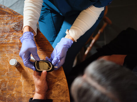 Native American nurse with blue latex gloves holds glucomter for patient