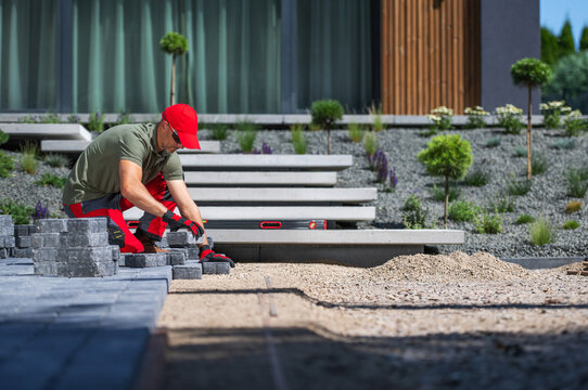 Man Laying Stones in Garden on Sunny Day Outside House