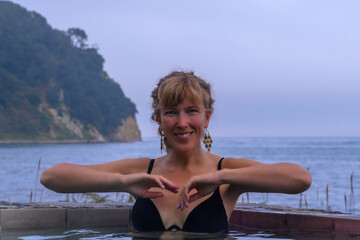Woman relaxing in hot springs by the sea coast in Russia during twilight hours