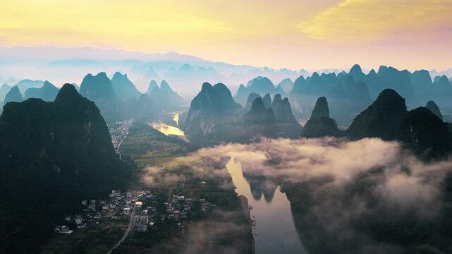 Aerial shot of the Li River winding through karst mountains and villages in Guilin, China at sunrise.