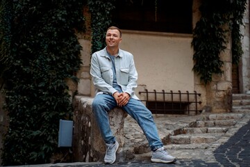 Fototapeta premium Smiling man sitting outdoors in historic European town