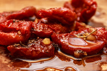 Macro texture of sun dried red tomatoes in olive oil with herbs and garlic. Appetizing vegetable preserve.