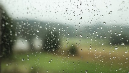 Obraz premium Raindrops on window with blurred green field
