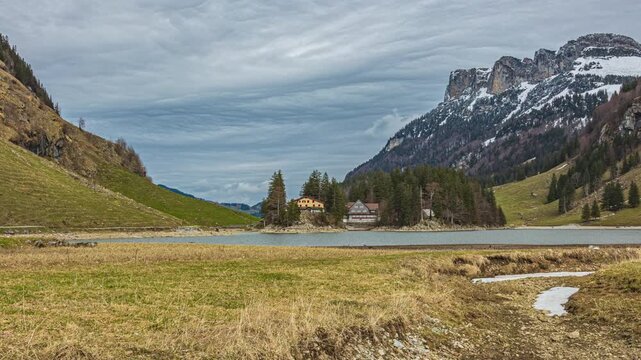 Time lapse, a scenic alpine lake surrounded by limestone cliffs and alpine pastures. Seealpsee view towards Berggasthaus Seealpsee, Appenzell Alps, Switzerland