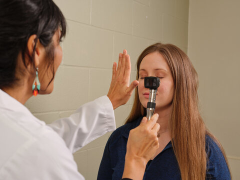 Native American NP performs eye exam on female patient