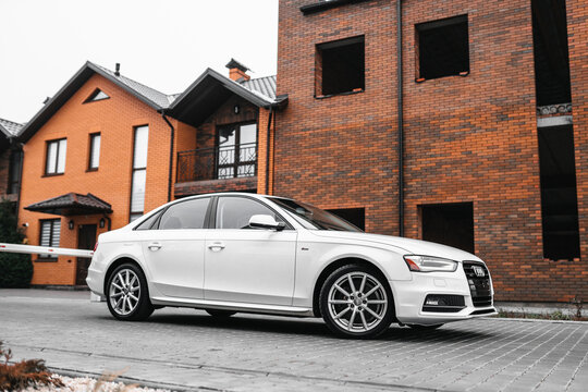 Vinnitsa; Ukraine; December 12, 2020: White Audi A4 (sedan; 4th generation; B8) standing on the street near the buildings. White car near the families houses
