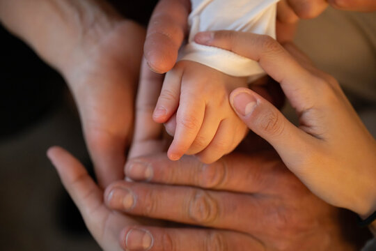 Close-up of newborn baby hand gently held by parents, symbol of love, family, care and protection. Tender moment of bonding, parenthood and new life.
