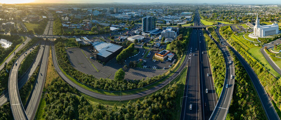 Aerial view of Manukau, Auckland, New Zealand, showing the city skyline, highway traffic, commercial buildings, and the Auckland New Zealand Temple. Illustrates urban planning and transportation. © Stefan