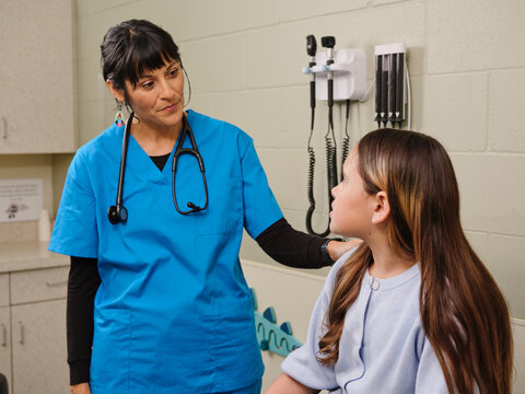 Native American nurse listens to young girl's health concerns in clinic