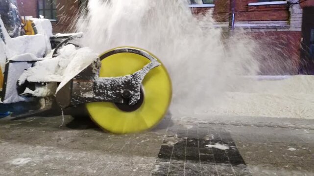 Snow blower working on street, close up. Utility services are clearing the city of snowdrifts. Evening outdoor