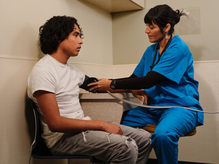 Teenage boy gets blood pressure measured by nurse