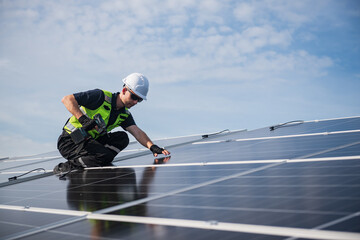 Technician installing solar panels on factory roof for green energy. A skilled technician in safety...