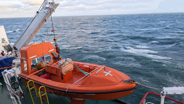 Orange Rescue Lifeboat Secured on Davit System of Ship at Sea