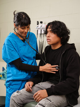Native American nurse performs cardiac exam on teen