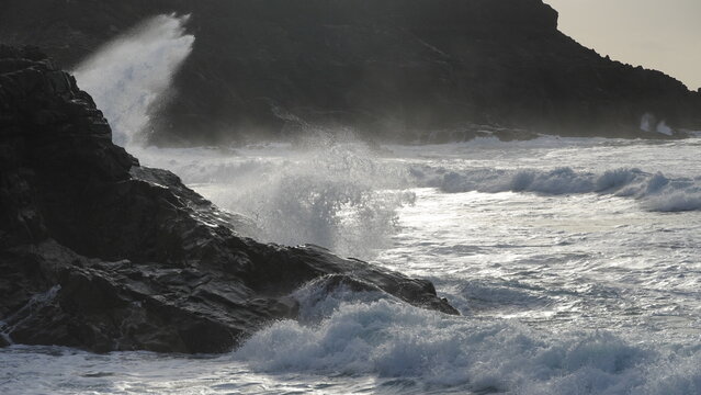 Spectacular sunset contemplating the force of the sea crashing agains the cliff