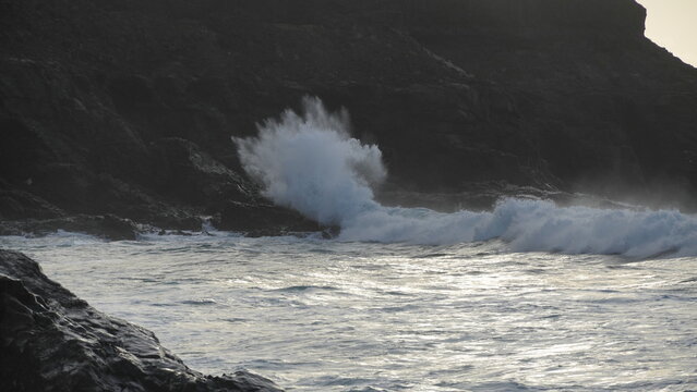 Spectacular sunset contemplating the force of the sea crashing agains the cliff