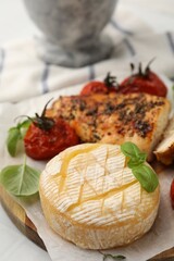Delicious roasted chicken breast, cheese, sun dried tomatoes and basil on table, closeup