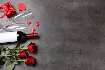 Beautiful roses, wine with glasses, gift and decorative hearts on grey background, flat lay. Space...