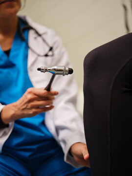 Indigenous nurse monitors woman's knee reflexes