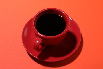 Cup of aromatic coffee on red background, above view