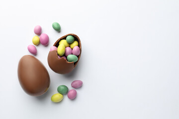 Obraz premium Chocolate Easter eggs and candies on white background, flat lay. Space for text
