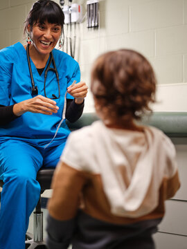 Native American nurse shows toddler boy the measuring tape in clinic