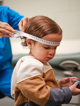 Native American nurse measures little boy's head during clinic exam