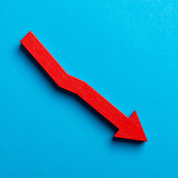 Red wooden arrow pointing downward, blue backdrop. Economic downturn, business, market decline