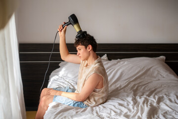 teenage boy blow-dries his hair, hair styling, personal care, hair dryer, concept everyday teen life