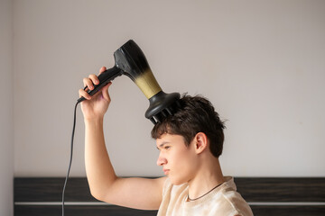 stylihe 17-year-old teenage boy blow-dries his hair, hair styling, personal care  concept