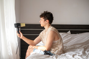 Fanny 17-year-old teenage boy blow-dries his hair, hair styling, teenage mood concept