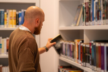 A bearded man  working and studying in a public library.