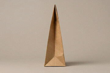 Side profile close up view of a tall triangular cardboard packaging structure on a neutral background