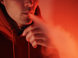 man exhales steam from an electronic cigarette, close-up