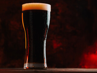 Brown beer ale in a tall glass on a dark background