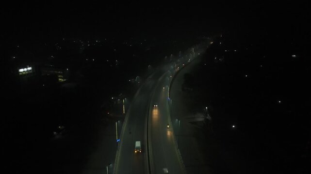 An aerial clip of a flyover with little traffic, captured at night with illuminating street lights, ascending drone, 4K horizontal footage. 