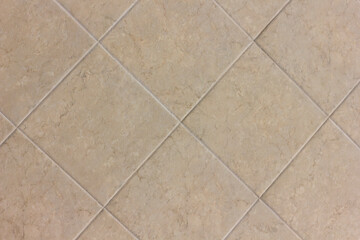 Fototapeta premium Texture of a wall made of beige square ceramic tiles laid out in a pattern close-up
