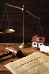 Last Will and Testament, gavel, scroll, house model and scales on wooden table, closeup