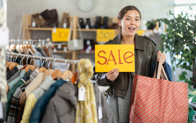 Discounts and promotions for summer collection of clothes and shoes at womens goods store, closing of trading season. Girl model with poster in hands announces mega sale
