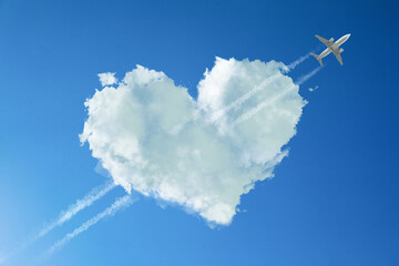 Cute fluffy heart-shaped cloud with plane flying through it as piercing arrow in blue sky